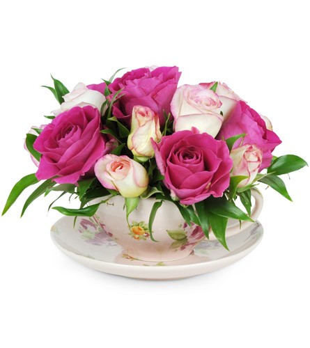 Teacup of Roses. An arrangement by Avenue Flowers and Gifts. Bright fuchsia roses and dainty pink spray roses are arranged in a delicate floral...